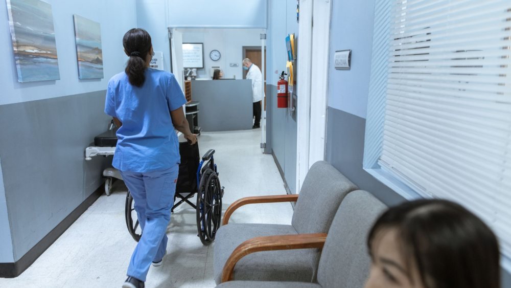 ممرضة تدفع مريضاً على كرسي متحرك في ممر مستشفى