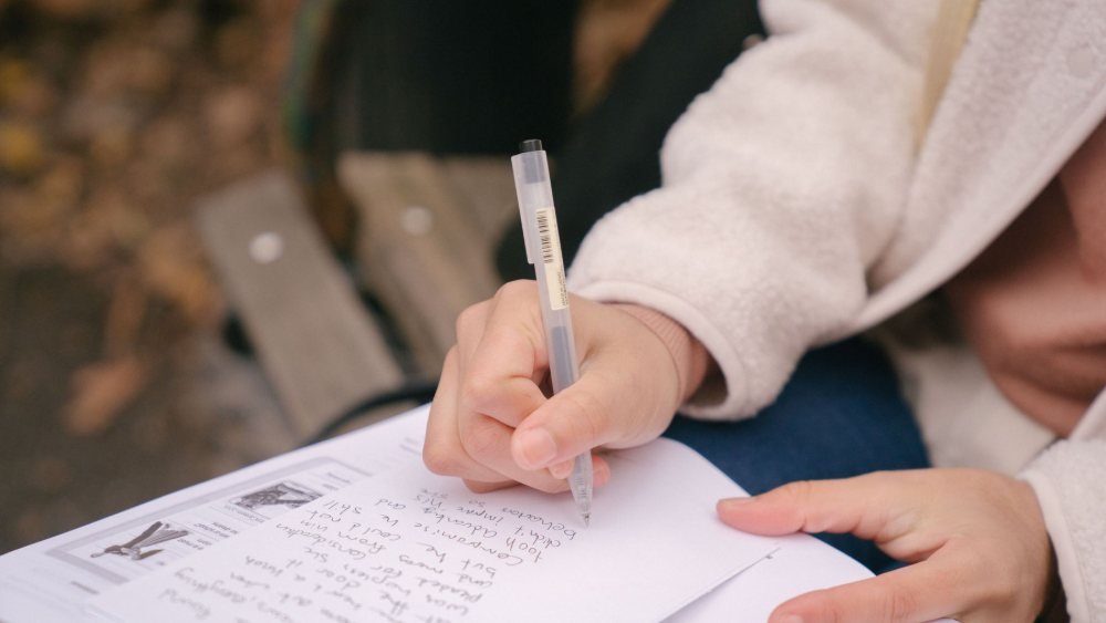 طالبة تراجع كتاب تعلم اللغة التركية وتكتب المفردات الجديدة